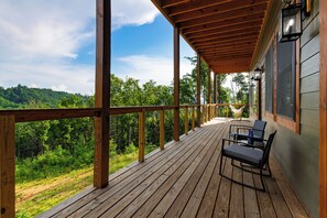 Eine Holzterrasse mit Blick auf einen Wald, eine Hängematte und Gartenmöbel.
