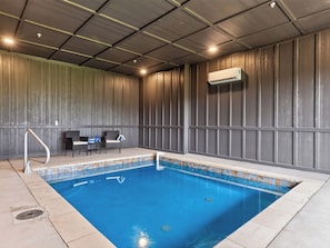 A swimming pool with a tiled edge, a chair, and a table with bottles. - Sleeps 40 + 2 Indoor Pools + Game Rooms | The Spurling Collection (Sevierville)