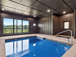 Ein Swimmingpool mit Blick auf eine bewaldete Landschaft durch große Fenster.