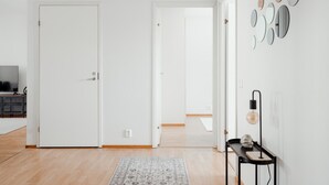 Huoneessa on puulattia, harmaa matto, televisio ja seinä, jossa on pyöreitä peilejä.
