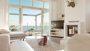 A modern living room with a large window, a flat-screen TV, and a fireplace. - Villa with Panoramic Water Views (Makkum)