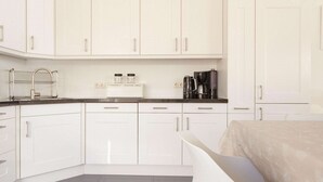A modern kitchen with white cabinets, a black countertop, and a coffee maker. - Villa with Panoramic Water Views (Makkum)