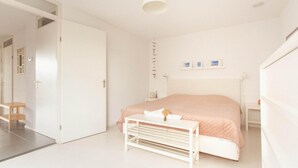 A minimalist bedroom with a bed, bedside table, and a hanging light fixture. - Villa with Panoramic Water Views (Makkum)