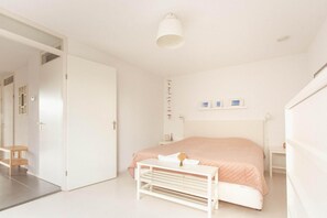 Ein schlicht eingerichtetes Schlafzimmer mit Bett, Nachttisch und einer Pendelleuchte.