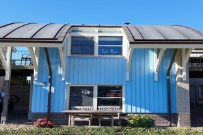A two-story building with a blue exterior, a covered outdoor seating area, and a visible entrance. - Villa with Panoramic Water Views (Makkum)