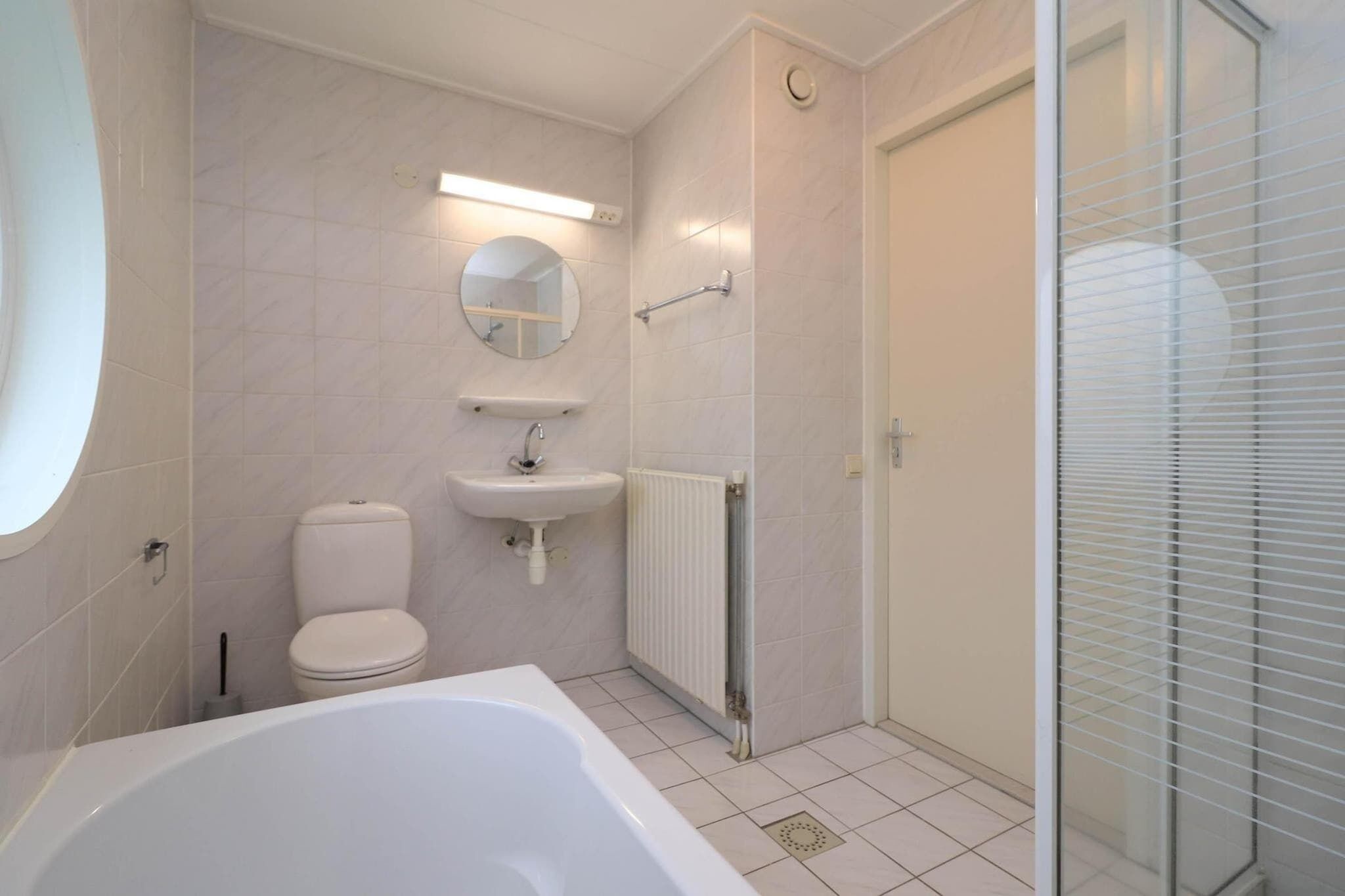 Ein modernes Badezimmer mit Badewanne, Toilette, Waschbecken und einer Duschkabine aus Glas.