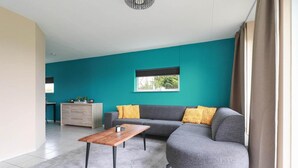 Ein modernes Wohnzimmer mit einem grauen Sofa, einem Holztisch und einer wandförmigen Aussparung in Türkis.
