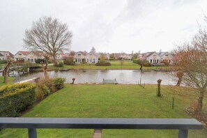 A residential area with houses, a pond, and a grassy lawn. - Comfortable 4-Person Bungalow with Jetty (Makkum)
