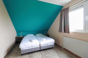A bedroom with a bed, two bedside tables, a window with curtains, and a radiator. - Comfortable 4-Person Bungalow with Jetty (Makkum)