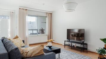 A modern living room with a sofa, TV, and a large window.