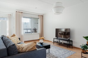 Una sala de estar moderna con un sofá, televisor y un ventanal grande.