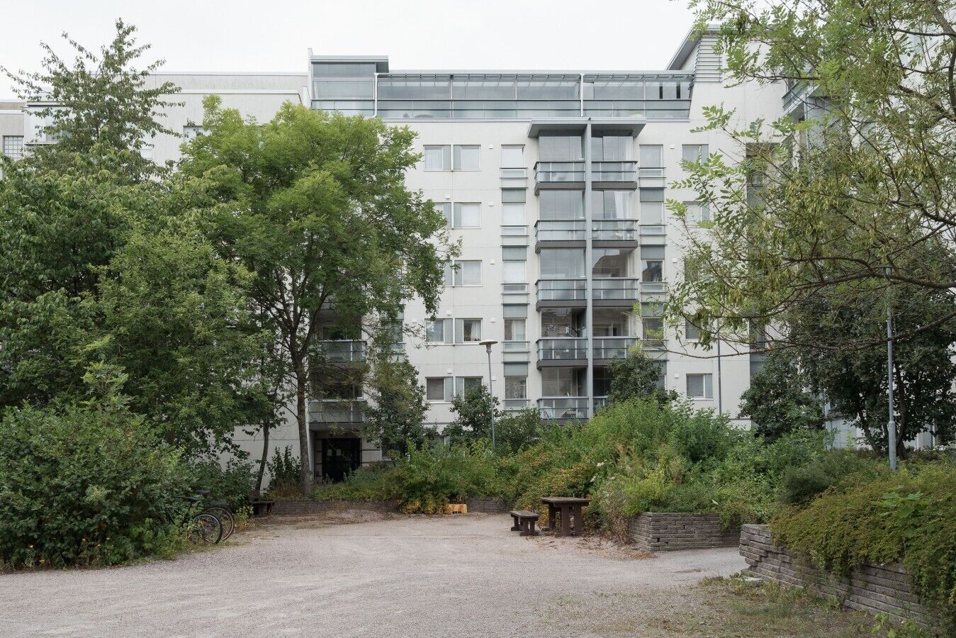 Ein modernes, mehrstöckiges Gebäude, umgeben von Grünflächen und einem Kiesweg.