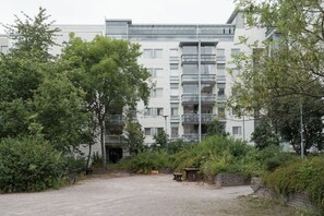Un edificio moderno de varios pisos, rodeado de vegetación y un camino de grava.