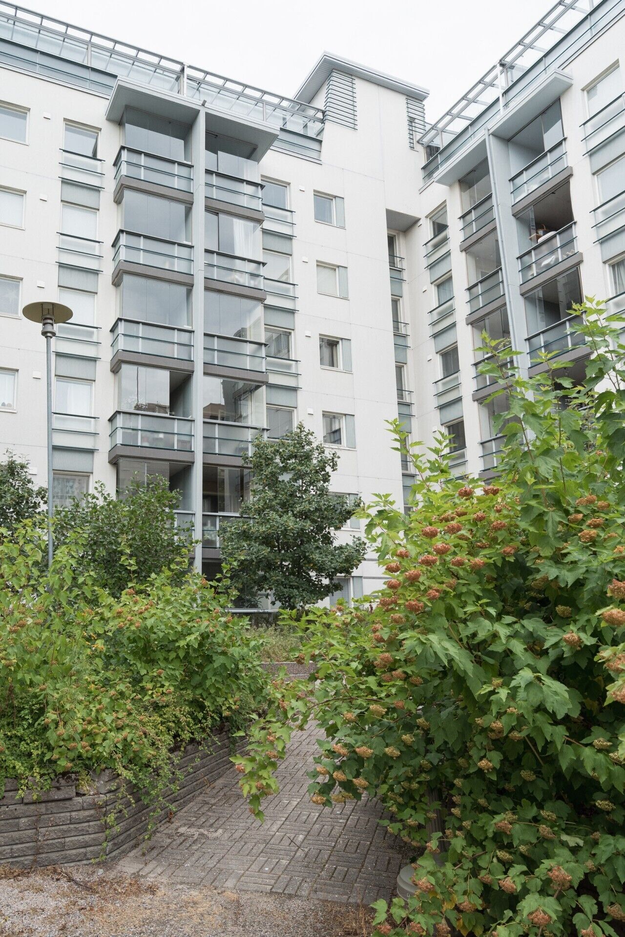 En modern flervåningsbyggnad med bostäder, balkonger och en gångstig av tegelstenar.