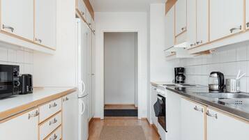 A narrow kitchen with white cabinets, a microwave, a coffee maker, and a toaster.