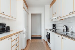 Una cucina piccola con mobili bianchi, un forno a microonde, una macchina da caffè e un tostapane.