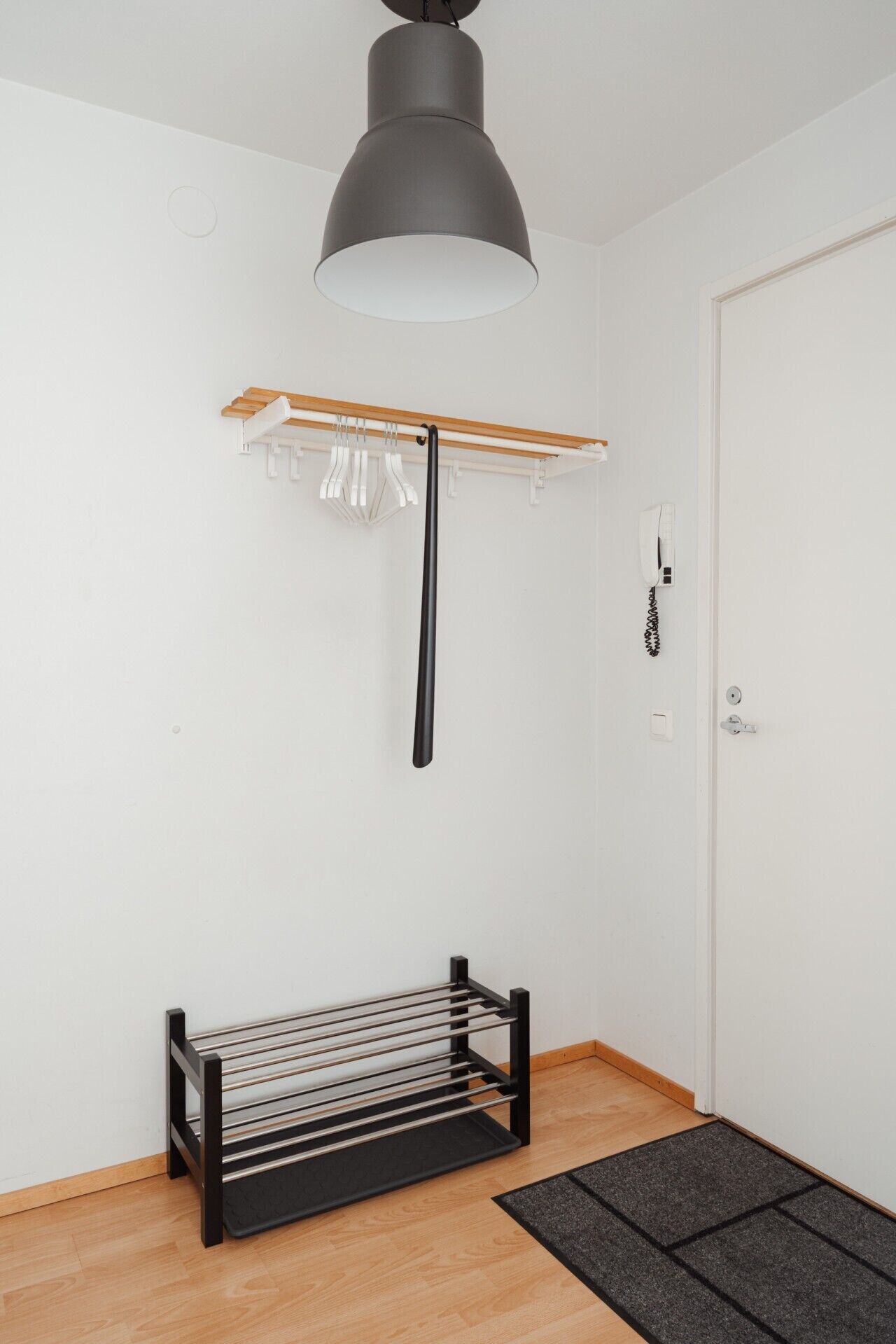 A room with a wooden bench, a coat rack, a door, and a ceiling light fixture.