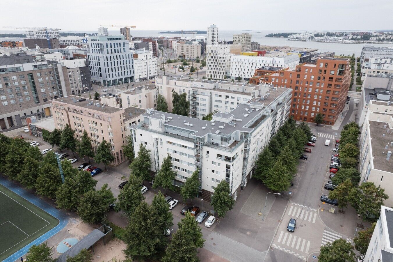 A multi-story building with a parking lot and trees in front.