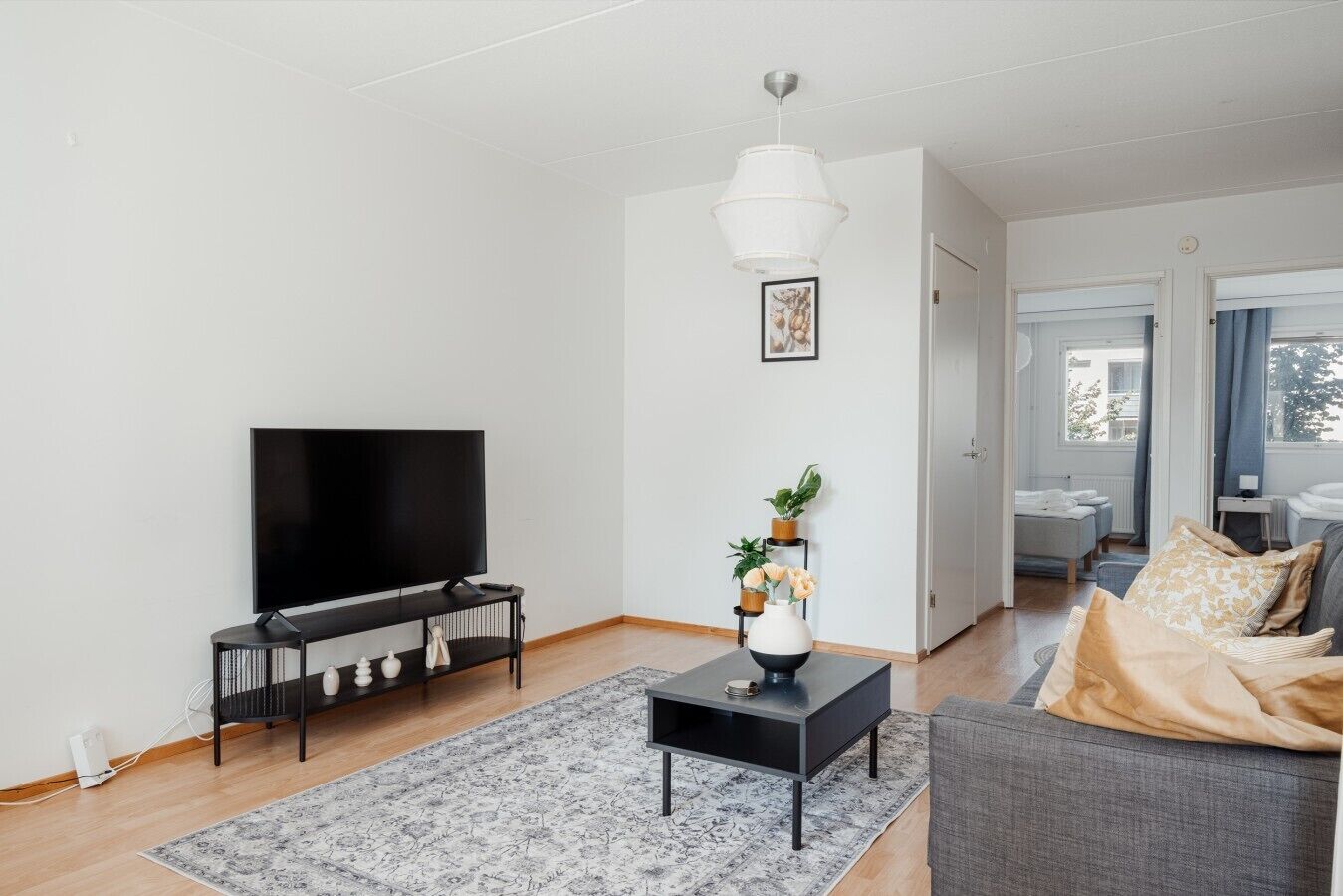 A modern living room with a flat-screen TV, a coffee table, a sofa, and a rug.