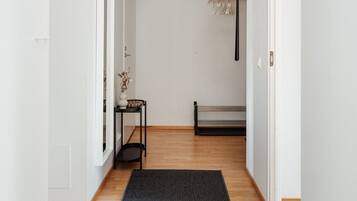 A hallway with a black rug, a bench, a small table with a vase, and a pendant light.