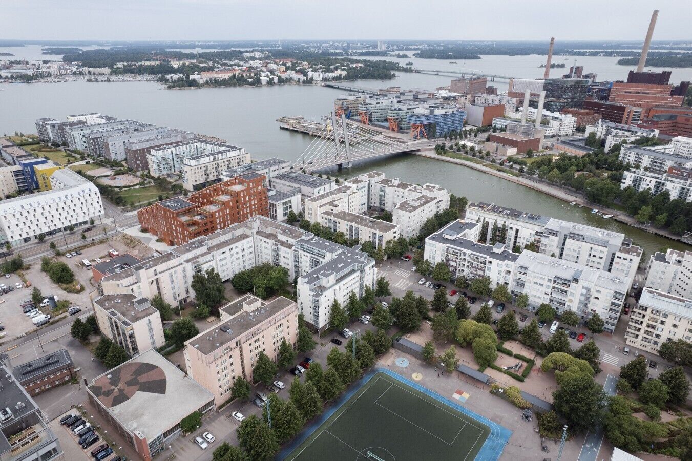 Oversigtsbillede af et boligområde med moderne bygninger, en flod og en bro.