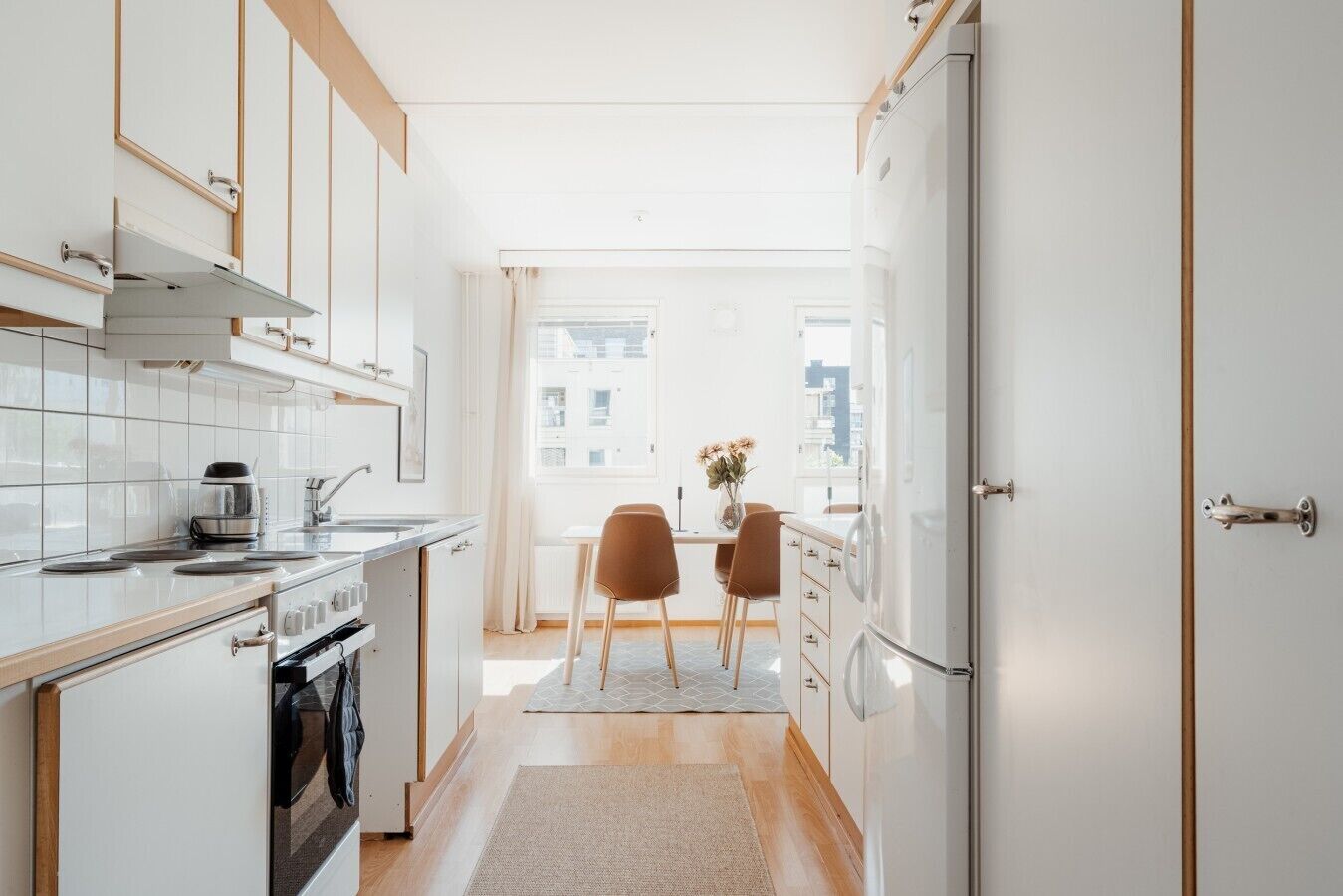 A narrow kitchen with a dining area, a stove, and a refrigerator.