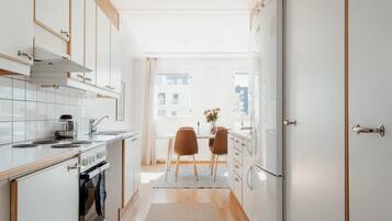 A narrow kitchen with a dining area, a stove, and a refrigerator.