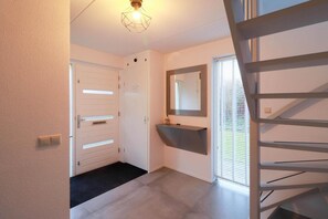 Ein Flur mit Tür, Spiegel, kleinem Waschbecken und Treppe.