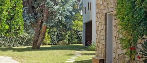 A house with a stone facade, a paved driveway, and a well-maintained lawn.