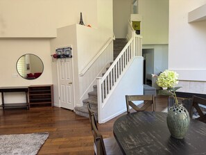 A living room with a staircase, a round mirror, a vase with flowers, and a wooden table. - Gorgeous 4-bed, 3 bath house with AC in lovely San Jose (San Jose)