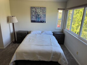 A bedroom with a bed, two nightstands, a lamp, and a window with a view of trees. - Gorgeous 4-bed, 3 bath house with AC in lovely San Jose (San Jose)