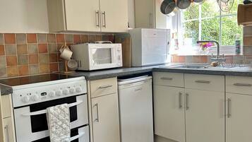 Een functionele keuken met een fornuis, magnetron en vaatwasser.
