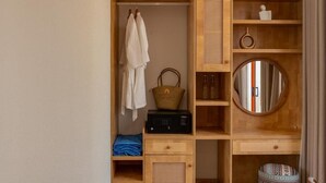 A wooden wardrobe with hanging robes, a basket, and a radio. - The Dome Hòn Thơm Hotel (Phu Quoc)