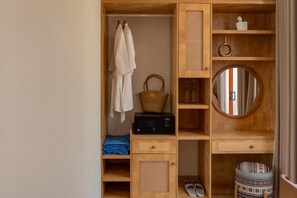 A wooden wardrobe with hanging robes, a basket, and a radio. - The Dome Hòn Thơm Hotel (Phu Quoc)