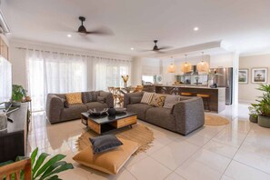 A modern living room with a grey sectional sofa, a coffee table, and a dining area with a kitchen in the background.