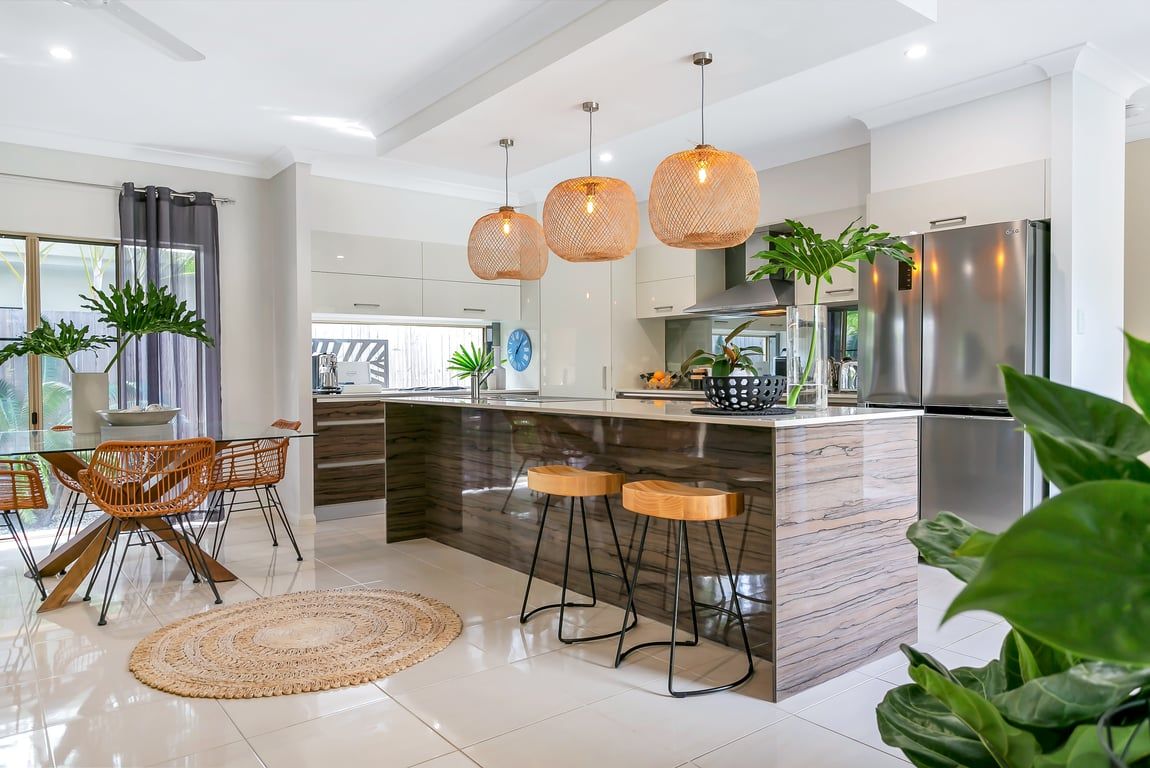 A modern kitchen with a central island, bar stools, pendant lights, and stainless steel appliances.
