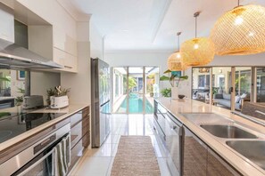 A modern kitchen with a glass door leading to a pool area.