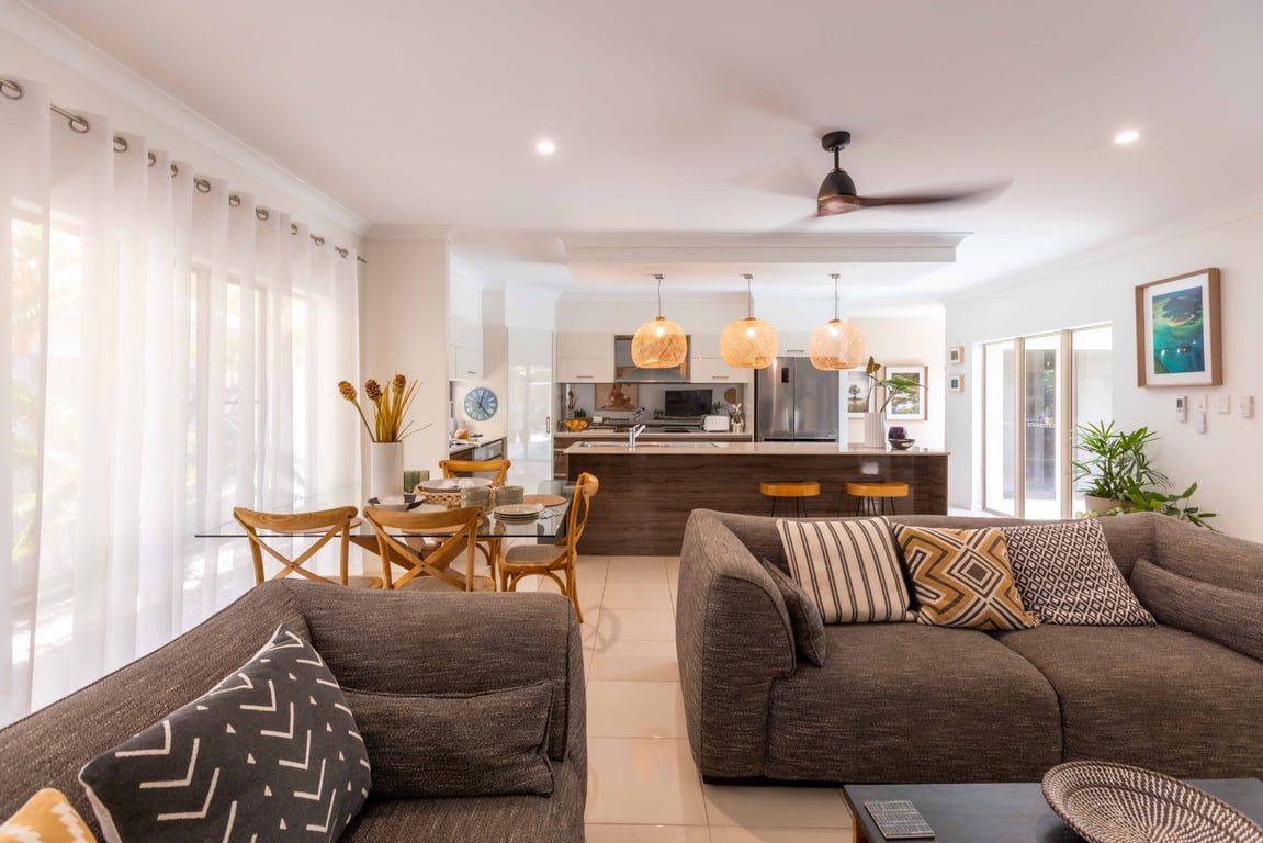 A modern living room with a sofa, a dining table with chairs, and a kitchen area in the background.