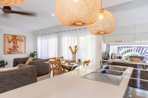 Une cuisine moderne dotée d’un îlot central, d’un évier en acier inoxydable et d’un coin repas avec une table et des chaises en verre.