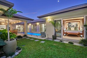A modern house with a swimming pool, outdoor seating, and a well-maintained garden.