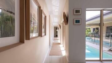 A hallway with framed artwork, a view of a pool, and a glass door leading outside.