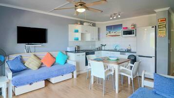 A compact living space with a kitchenette, a dining area, and a seating area with a sofa and chairs.