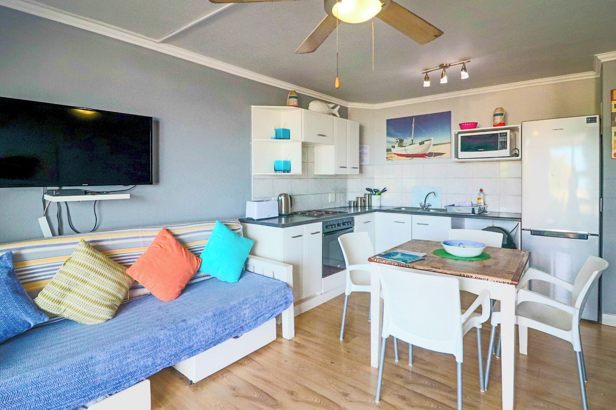 A compact living space with a kitchenette, a dining area, and a seating area with a sofa and chairs.