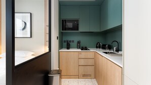 A compact hotel room with a bed, a small kitchenette, a microwave, a kettle, a toaster, and a trash bin. - Sleek Studio w/ Burj Khalifa View (Dubai)