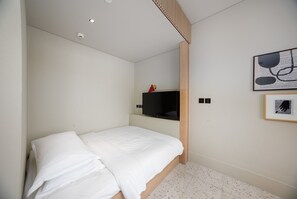 A bedroom with a single bed, a television on a shelf, and a framed picture on the wall. - Modern Studio Near Downtown | Burj View (Dubai)
