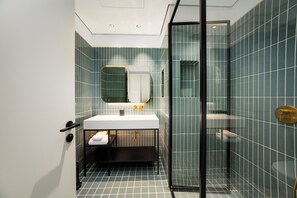 A modern bathroom with a glass shower enclosure, a white sink, and a large mirror. - Chic City Studio in Upside w/ Burj View (Dubai)