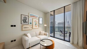 A modern living room with a sofa, a coffee table, and a large window with a city view. - Chic City Studio in Upside w/ Burj View (Dubai)