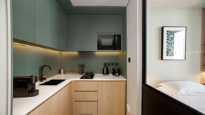 A compact kitchen with a microwave, sink, and wooden cabinets. - Furnished Business Bay Studio w/ Balcony (Dubai)
