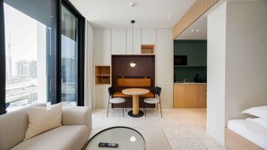 Een moderne hotelkamer met een bank, een ronde tafel, een zithoek en uitzicht op de stad.