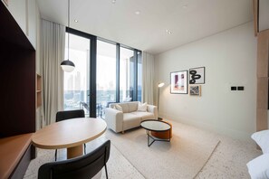 A modern hotel room with a sofa, a round table, and a view of the cityscape through large windows. - Executive Studio w/ Burj Khalifa View (Dubai)